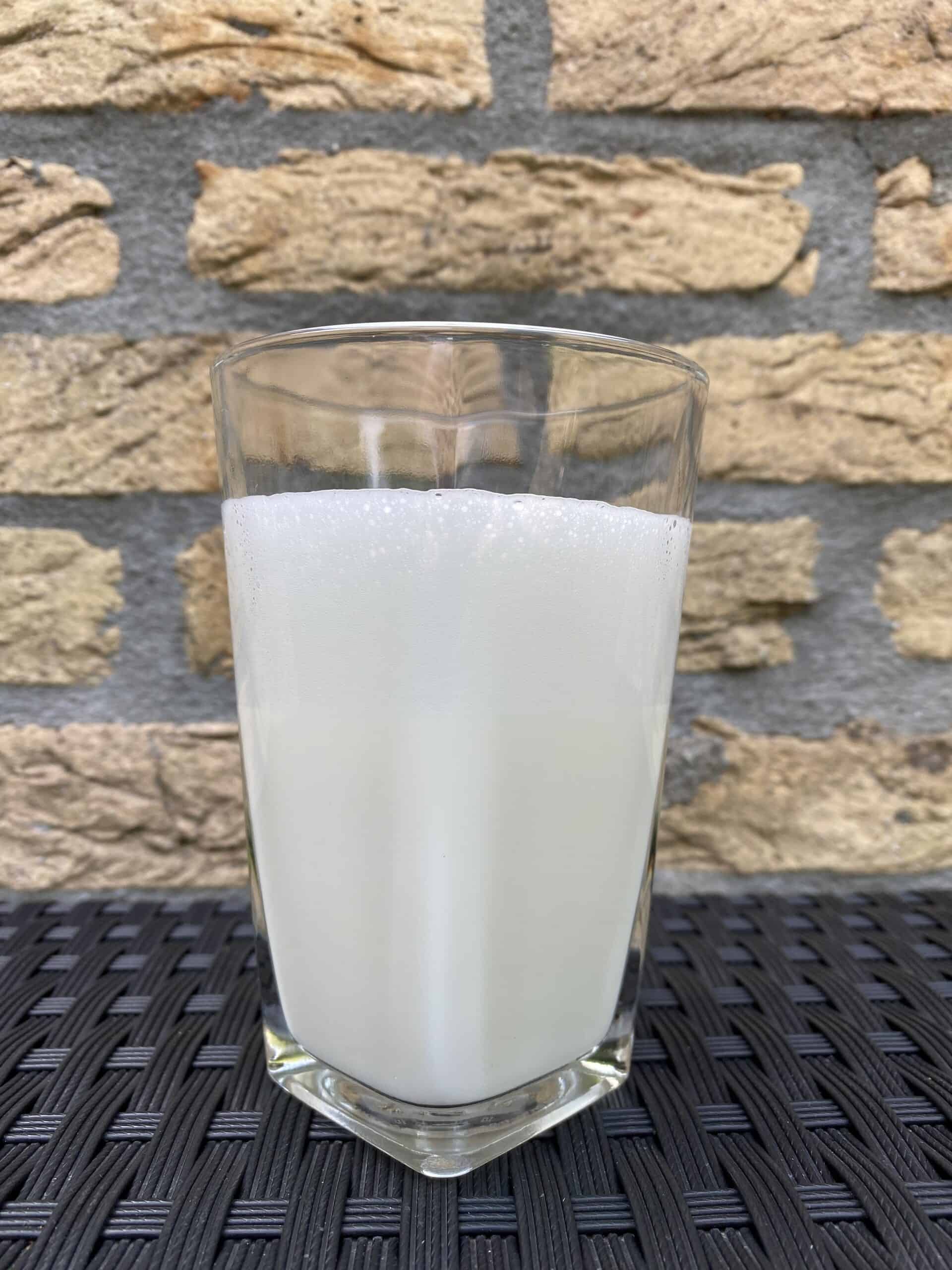 Adding freshly steamed milk to a glass.