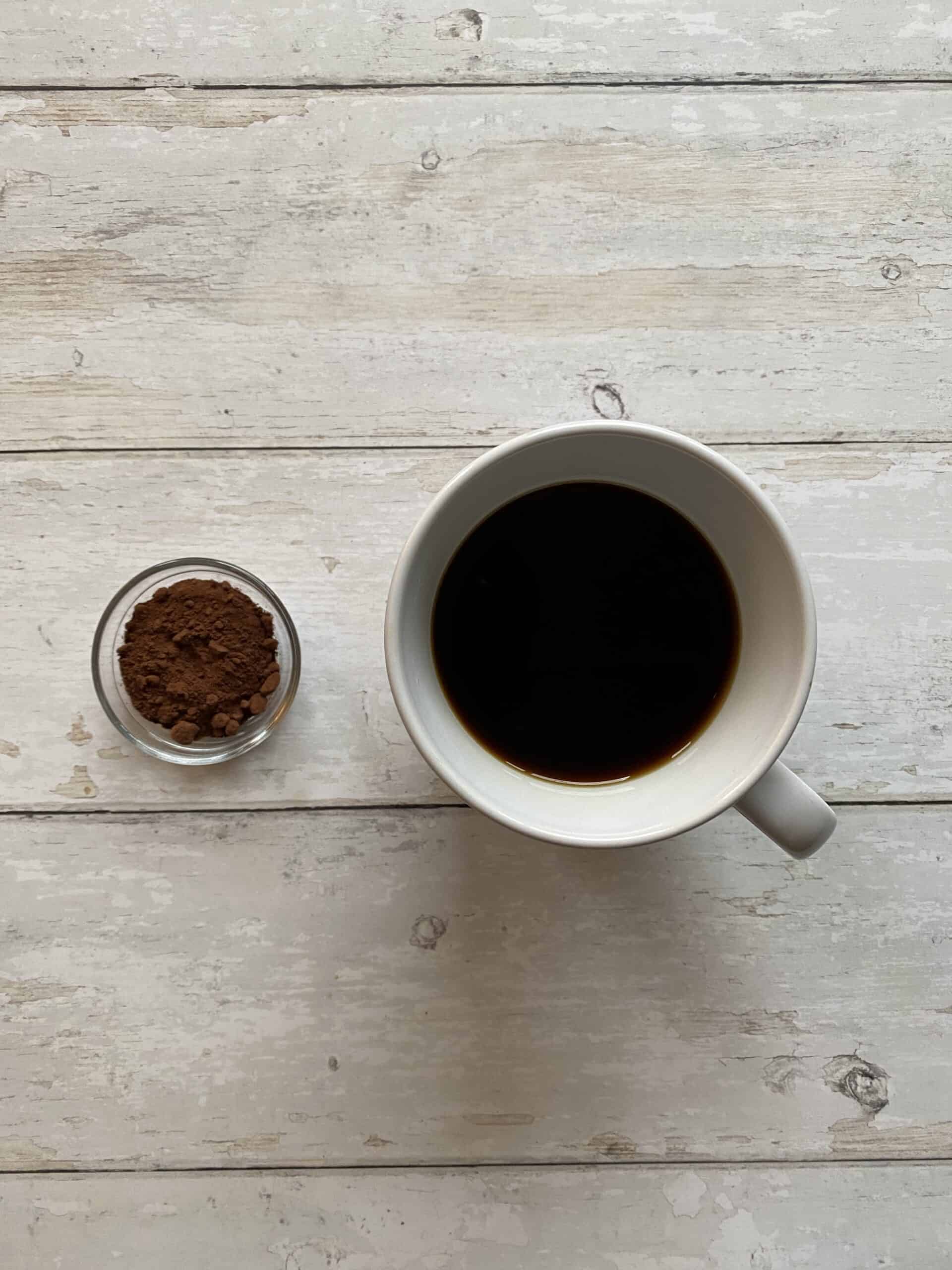 Cocoa powder next to freshly brewed coffee.