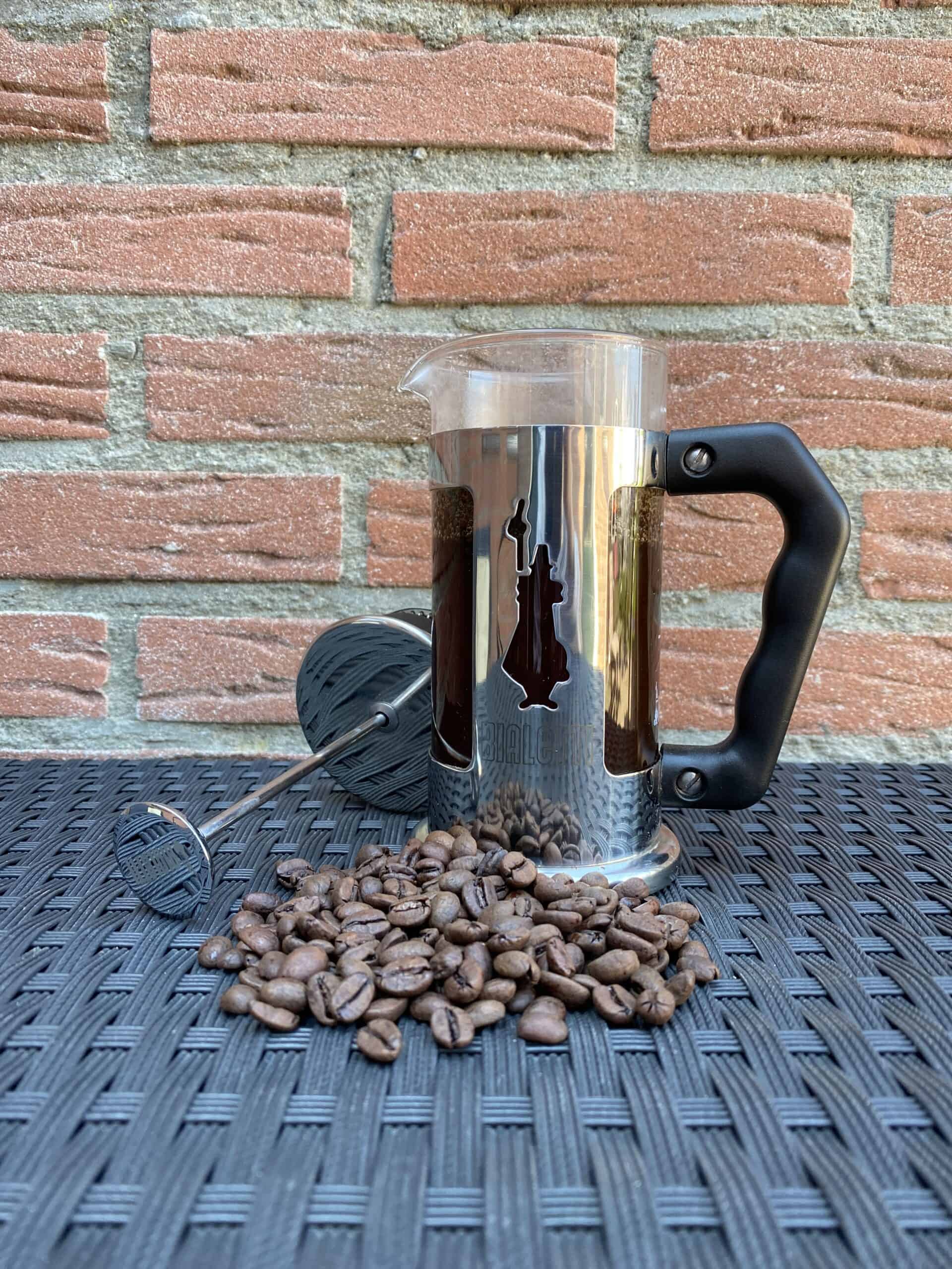 Brewing French press coffee with coffee beans in the front.